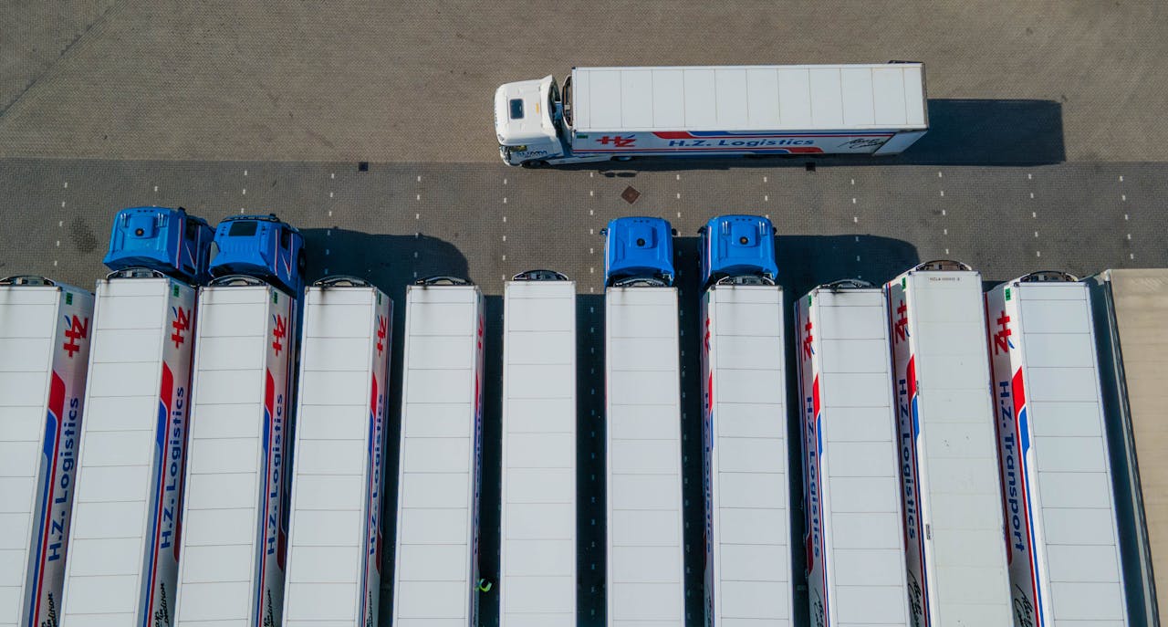 services-03 Top-down drone shot of logistics trucks arranged in a row in a parking lot.